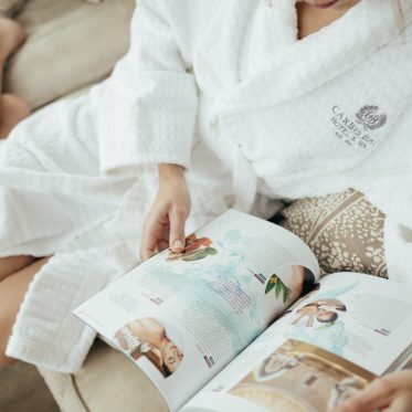 Spa guest in robe reading magazine.