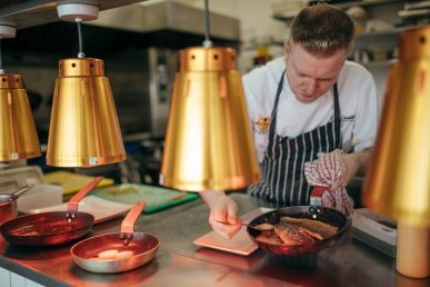 Chef at pass portioning meals.