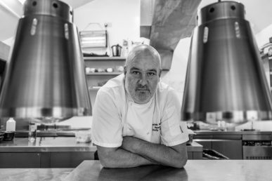 Black and white shot of chef leaning towards camera.