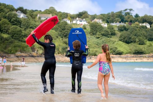 Kids playing with bodyboards on Carbis Bay beach.