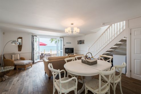 Beach house with dining area and staircase behind.