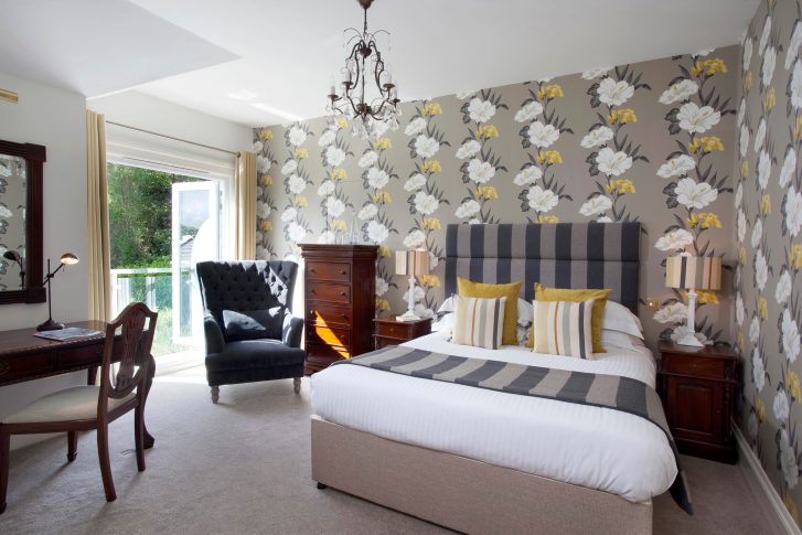 Double bedroom with window in the corner behind armchair.