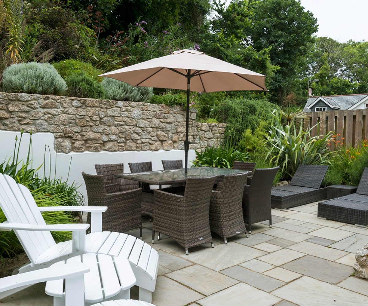 Patio area with garden furniture and stone wall behind.
