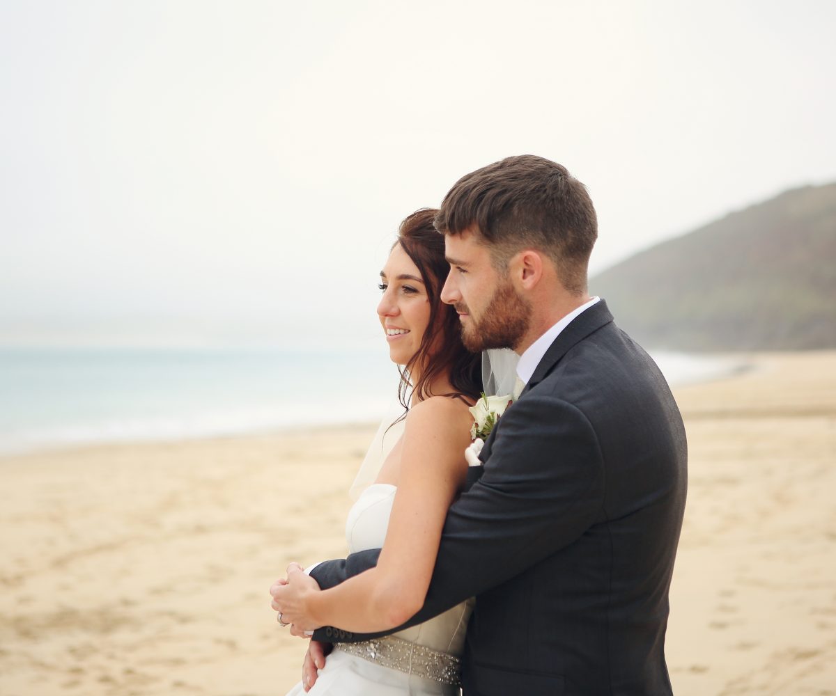 Newlyweds cuddling on Carbis Bay Beach.