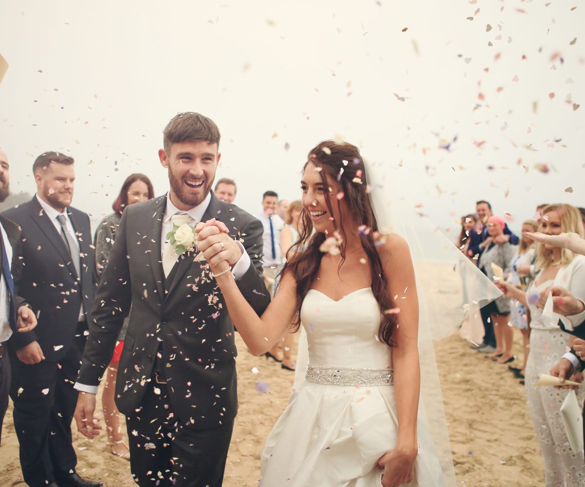 Confetti on bride and groom on beach.