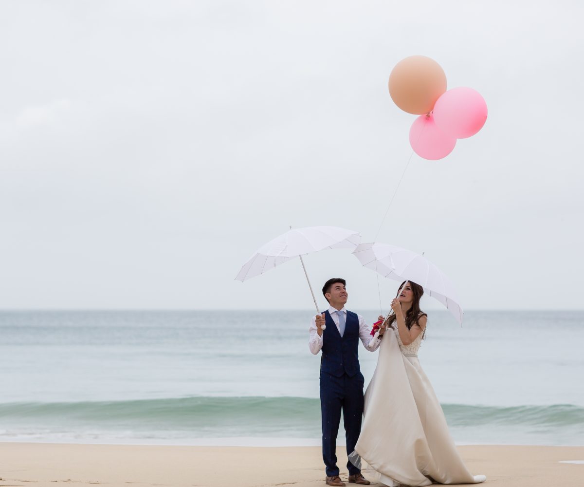 Bride and groom with pink balloons on Carbis Bay beach.