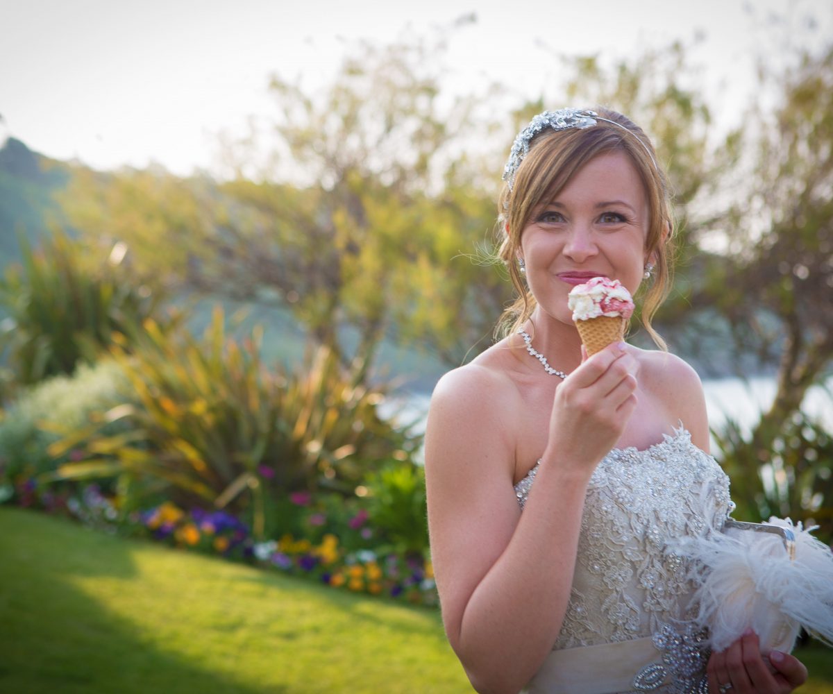 Bride enjoying ice cream cone with lawn behind.