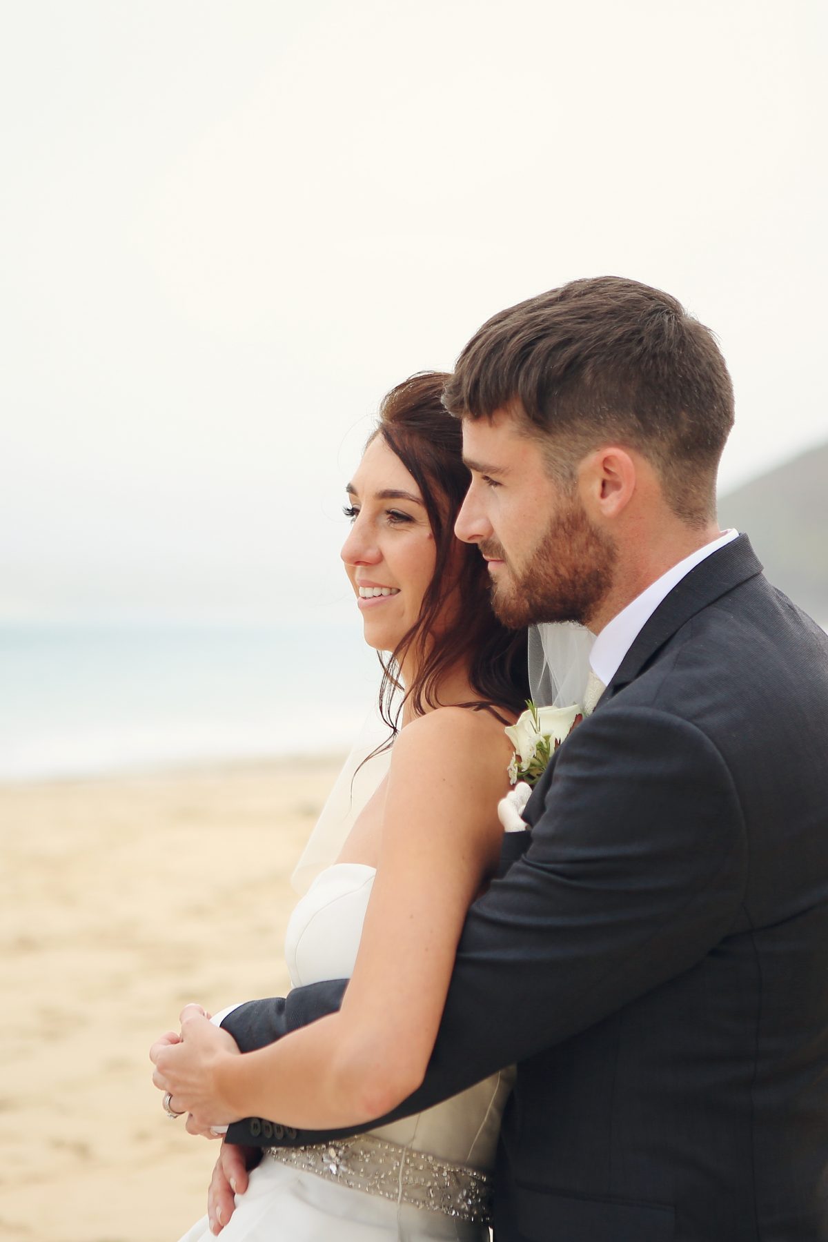 Newlyweds cuddling on Carbis Bay Beach.