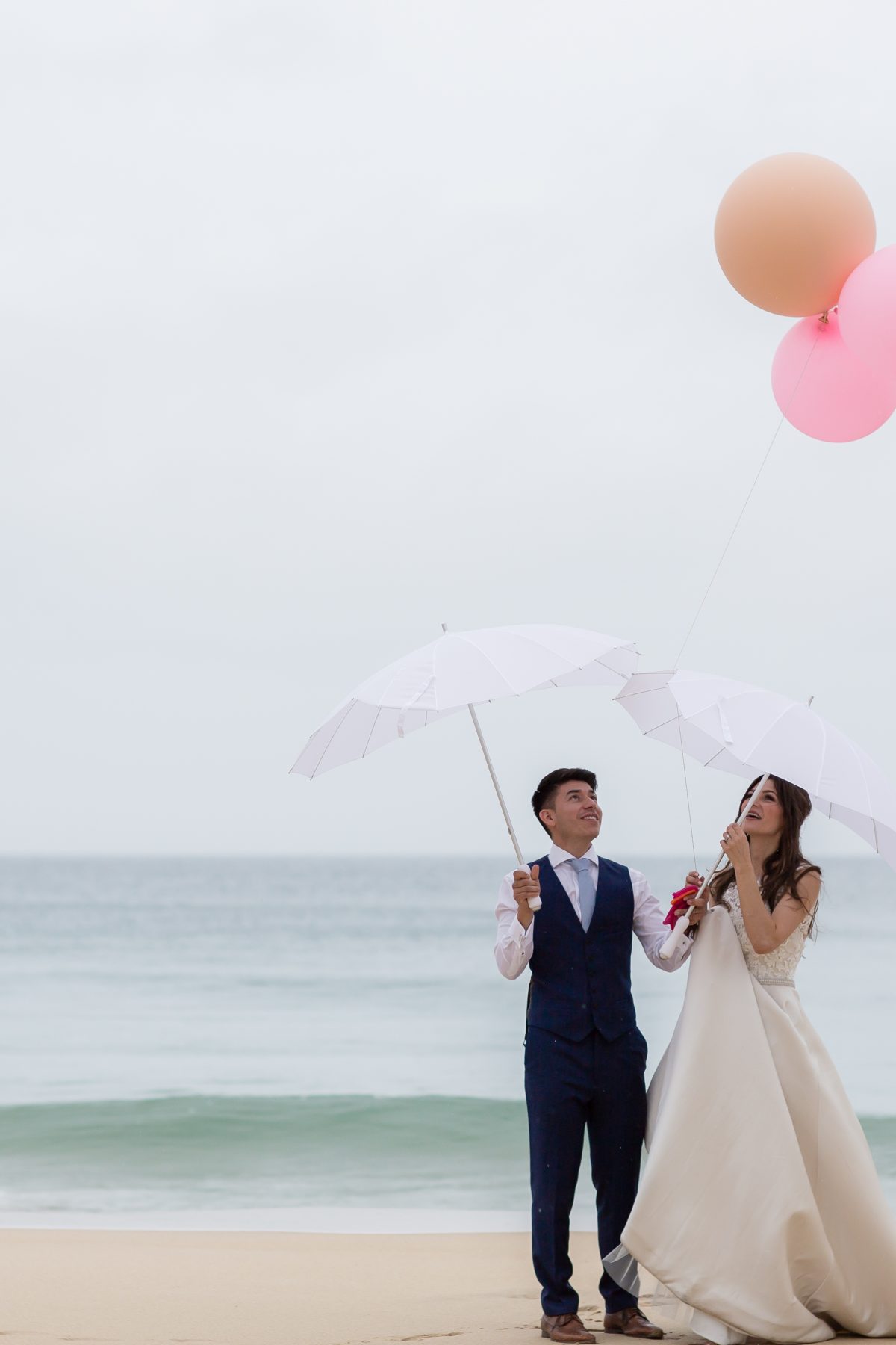 Bride and groom with pink balloons on Carbis Bay beach.
