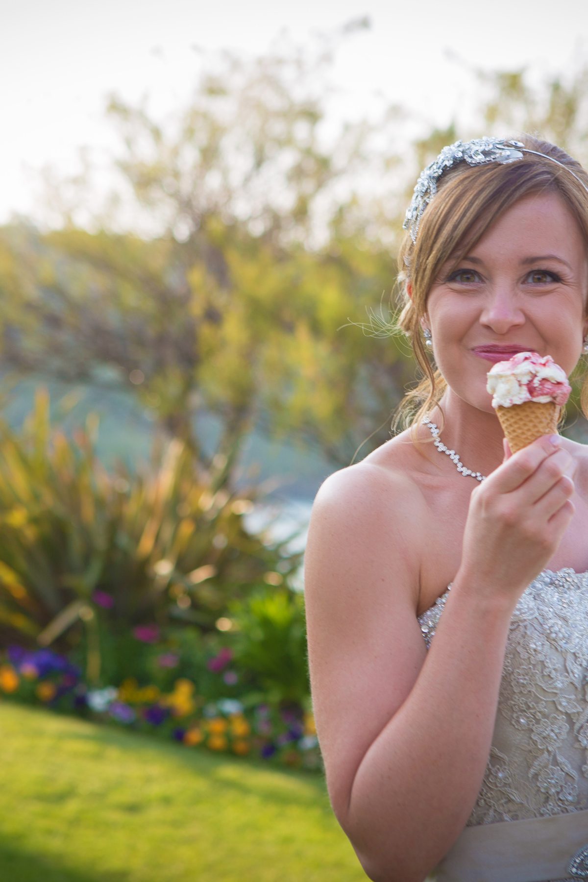Bride enjoying ice cream cone with lawn behind.