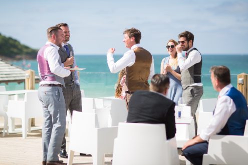 Groomsmen chatting with sea in the background.