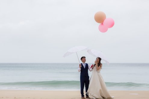 Bride and groom with pink balloons on Carbis Bay beach.