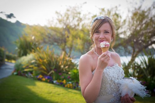 Bride enjoying ice cream cone with lawn behind.