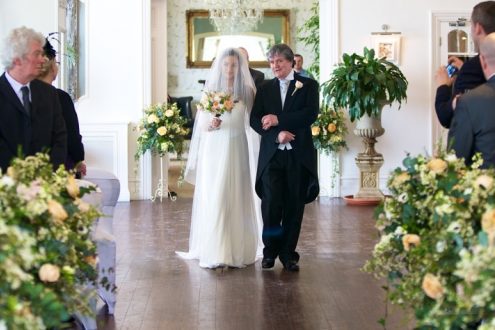 Bride and groom at alter with yellow flower decorations.