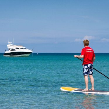 Stand up paddle boarder with yacht