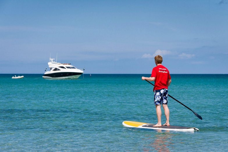 Stand up paddle boarder with yacht